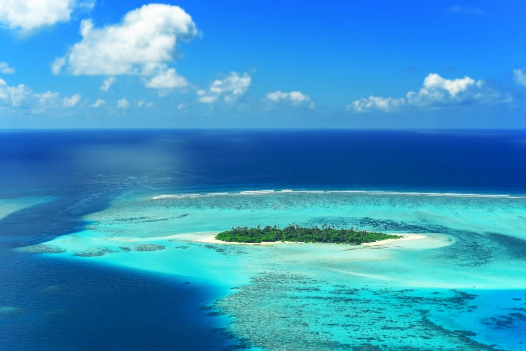 A stunning aerial view captures a lush island surrounded by turquoise waters in the Maldives.