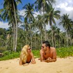 Couple enjoying a sunny day on a picturesque beach in Thailand surrounded by palm trees.